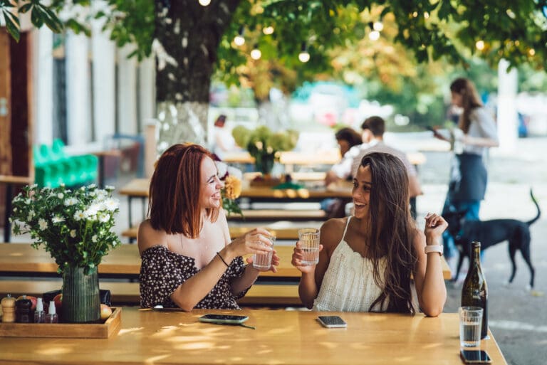 Two young beautiful women girlfriends talking in an outdoor cafe
