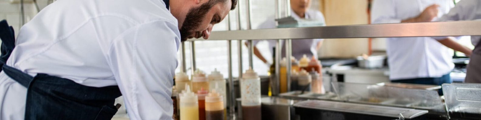 Chef writing in busy kitchen.